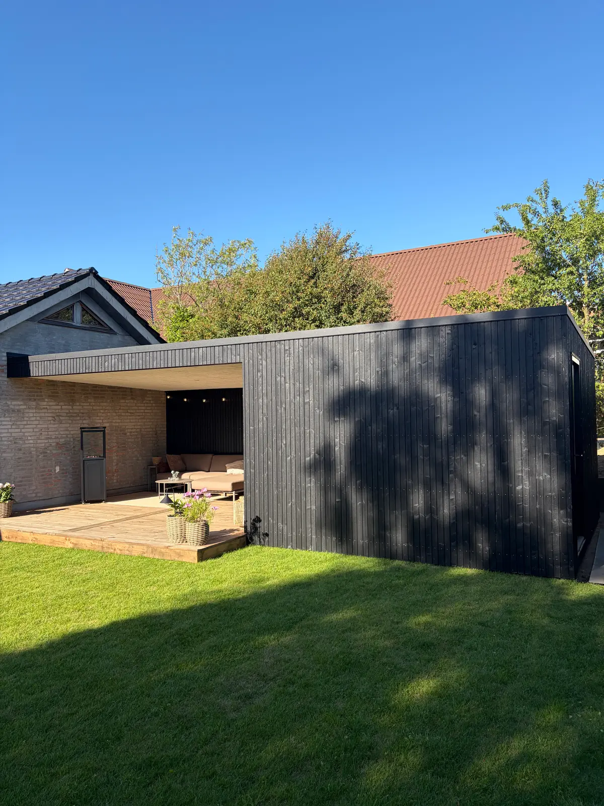 Sort pavillon set fra den anden side af haven