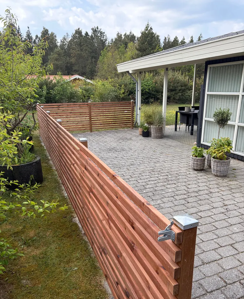 Vandret træhegn langs en flisebelagt terrasse